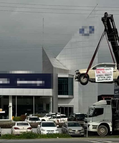 Aldığı sıfır kamyoneti, hatalı çıktığını öne sürüp, bayinin önünde vinçle kaldırarak sergiledi
