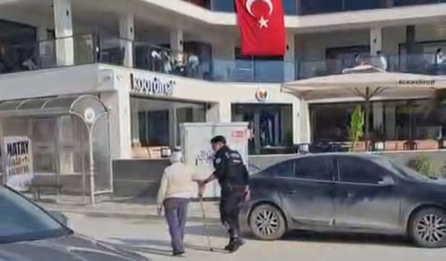 Hatay'da polisin, yolun karşısına geçmekte zorlanan kişiye yardım ettiği anlar kamerada