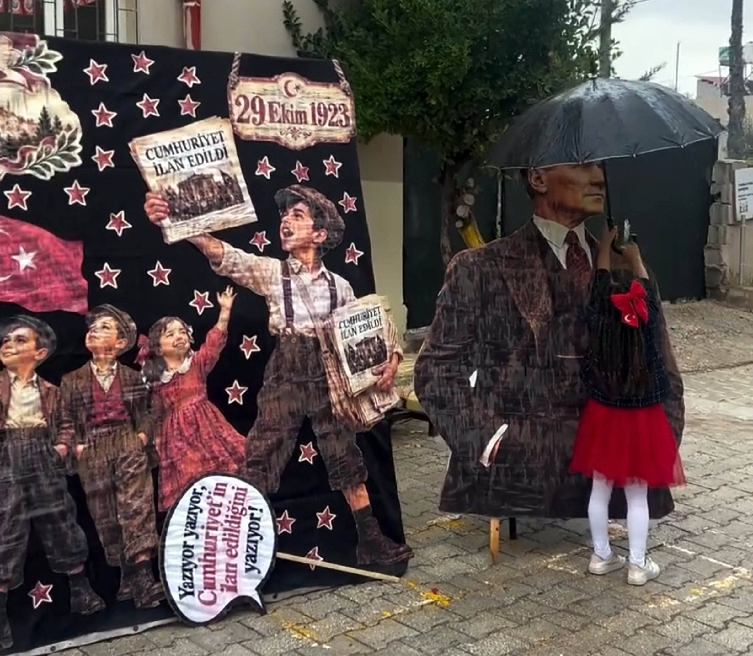 Yağmurda Atatürk maketini şemsiyeyle korudu